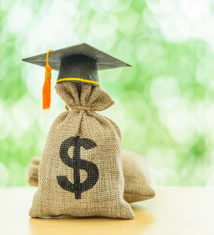 Education Or Student Loan, Financial Aid And Scholarship Concept : Mortarboard Or Graduation Cap On Top Of A Us Dollar Cash Bag. Depicting Financial Assistance For A Student's Tuition And Other Costs.